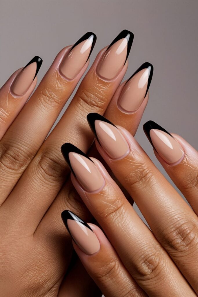 Nails painted in nude with bold black tips creating a chic and edgy modern look