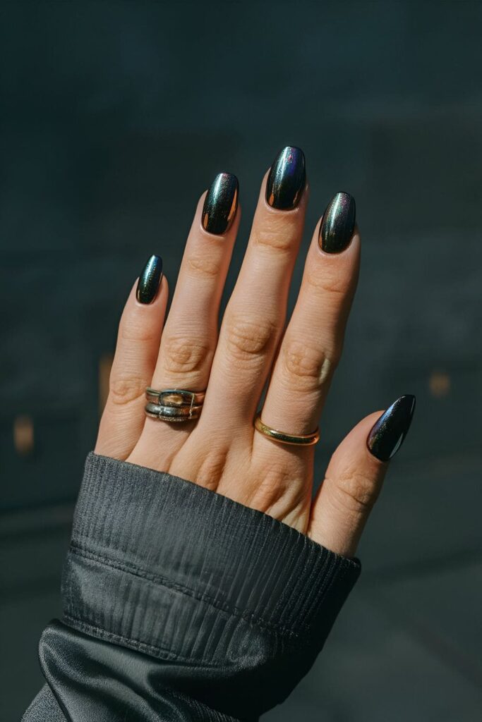 Nails with a dark base color, featuring a mix of metallic or duochrome polishes, creating a swirling, oil spill effect