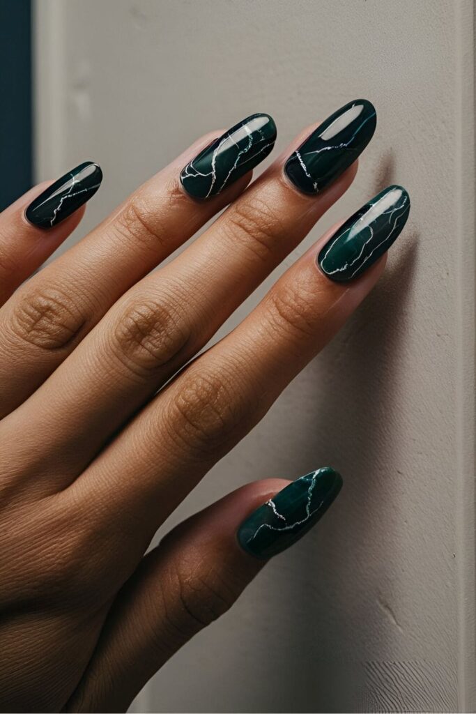 Nails with a dark marble effect in colors like black, deep blue, or dark green, with white veins creating a sophisticated and edgy look