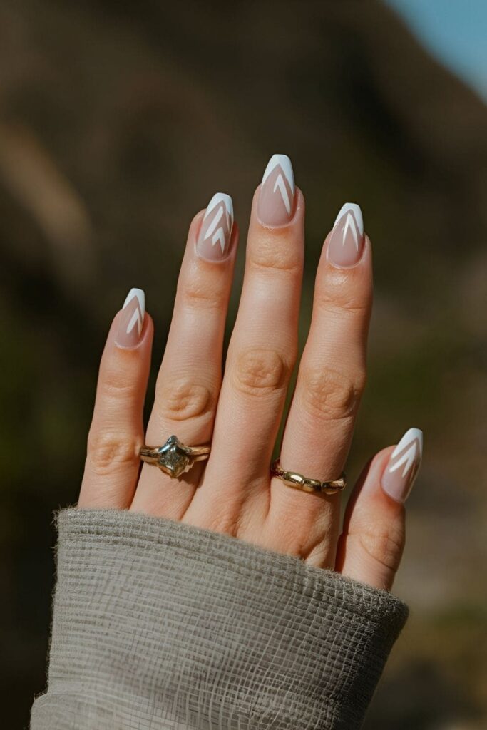 Nails with a neutral base and small mountain peak shapes in a contrasting color for a nature-inspired minimalist design