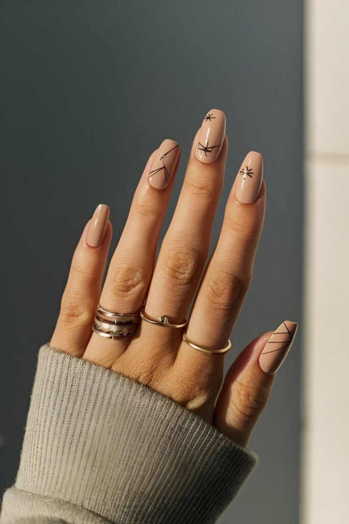 Nails with a nude base and small origami shapes, like cranes or boats, in black or metallic shades for an elegant, creative design