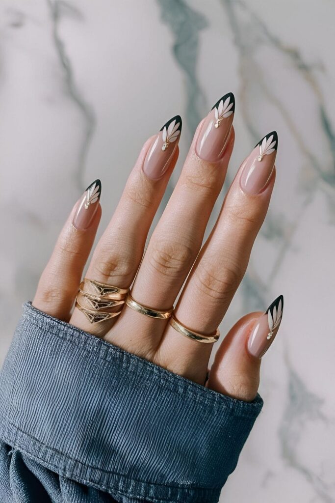 Nails with a nude base and small wing shapes in white or black metallic shades, giving a delicate and ethereal minimalist design