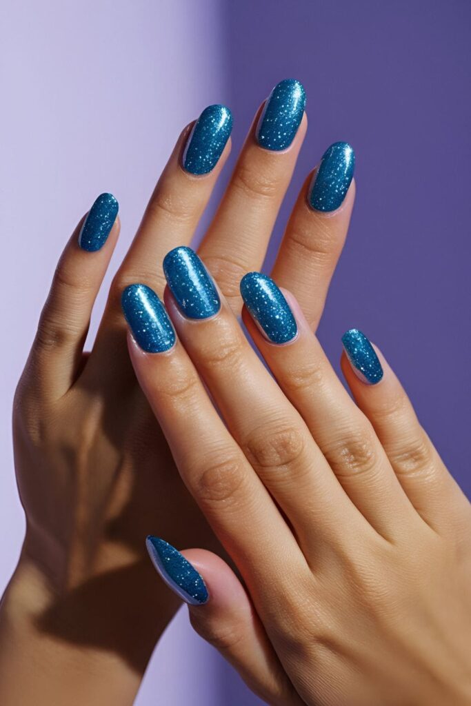 Nails with vibrant ocean blue glitter, sparkling under light