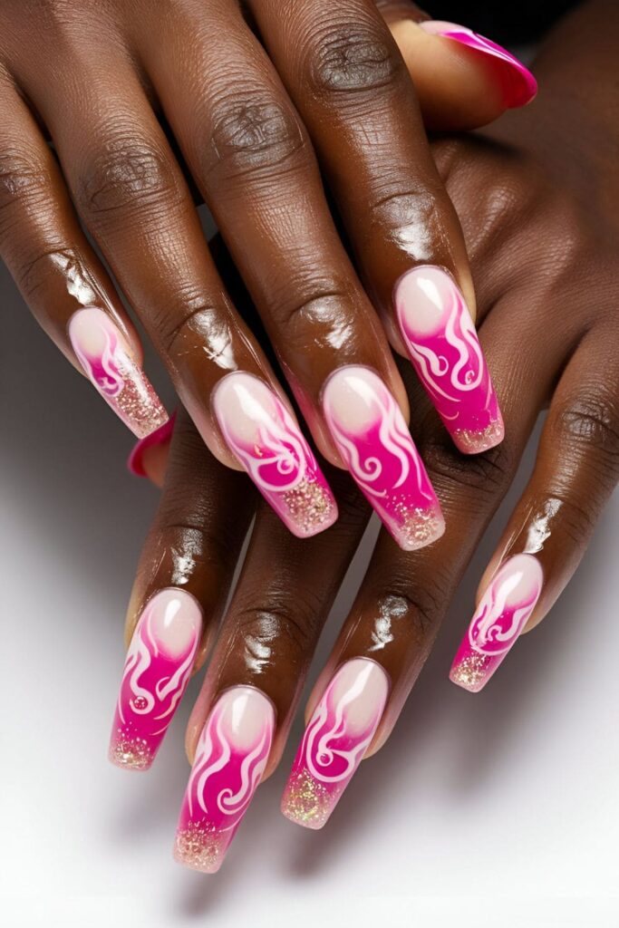 Pink acrylic nails with flame designs and glitter accents, creating a bold and sparkly look for dark skin tones