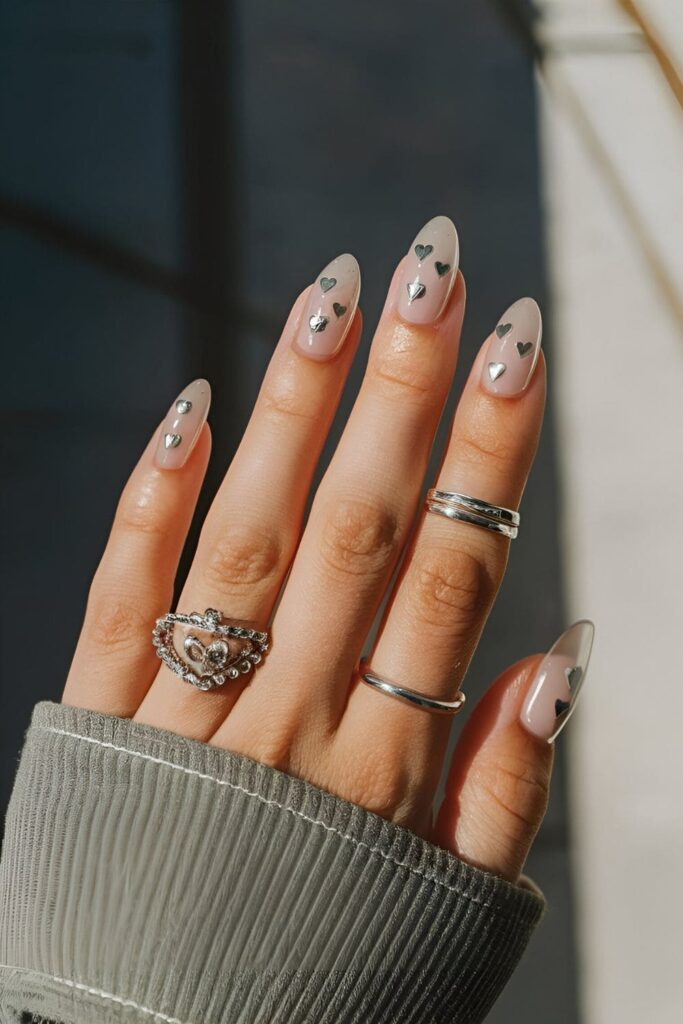 Romantic nails featuring small silver heart accents on a clear or colored base, perfect for Valentine’s Day