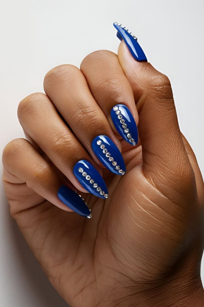 Royal blue nails adorned with tiny rhinestones at the base or in intricate patterns, adding a luxurious and glamorous touch with sparkling rhinestones