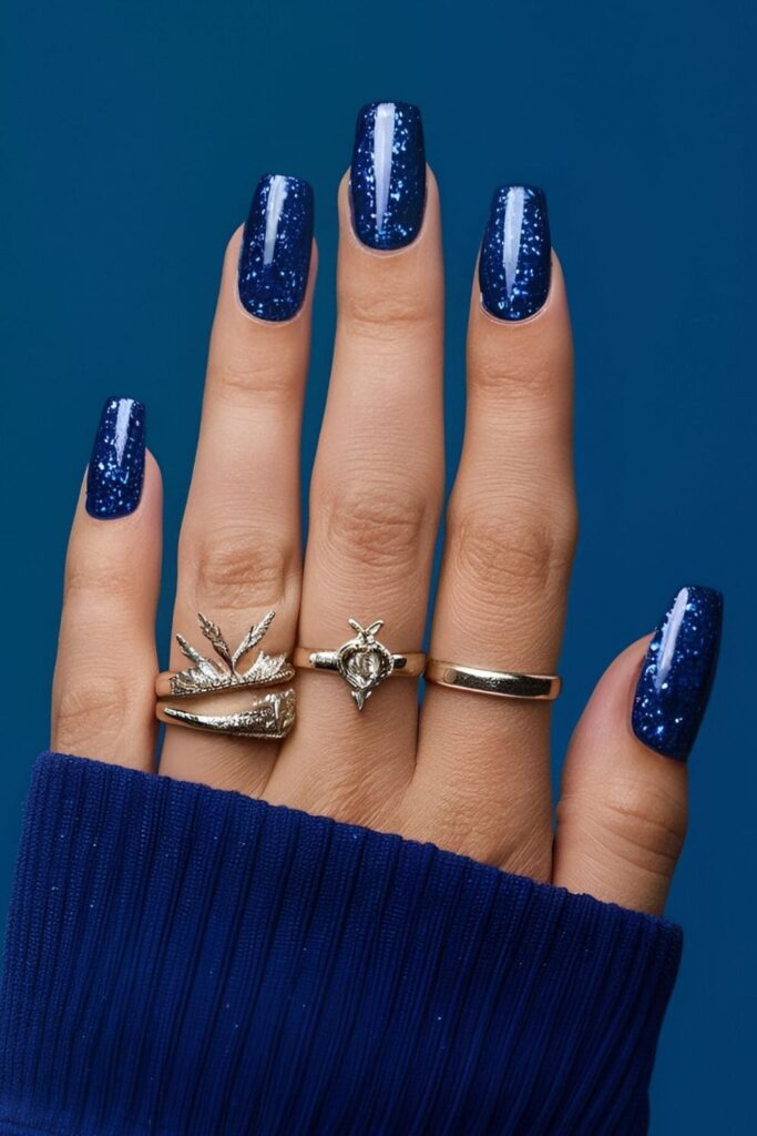 Royal blue nails covered in glitter polish, creating a dazzling effect with extra sparkle for a festive and glamorous appearance