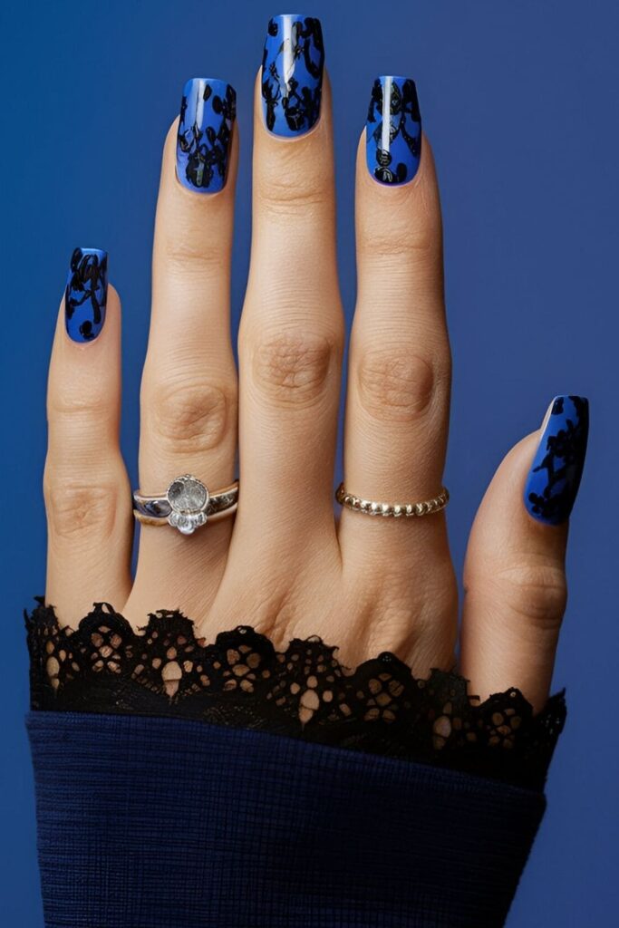 Royal blue nails with black lace patterns, adding sophistication and a chic edge with dramatic lace designs