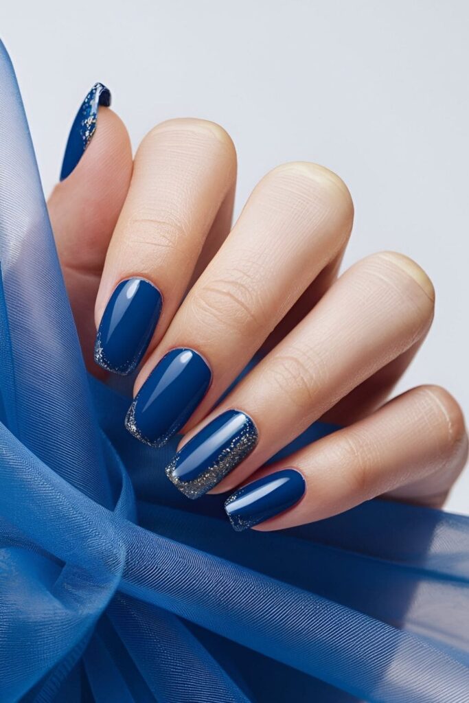 Royal blue nails with glittery tips in gold or royal blue glitter, adding subtle sparkle and glamour with shimmering tips