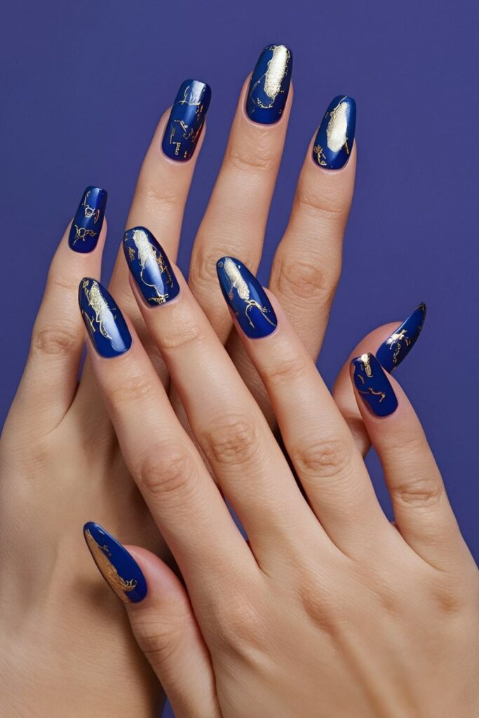 Royal blue nails with random patches or specific designs in gold foil, adding luxurious opulence with shiny gold accents