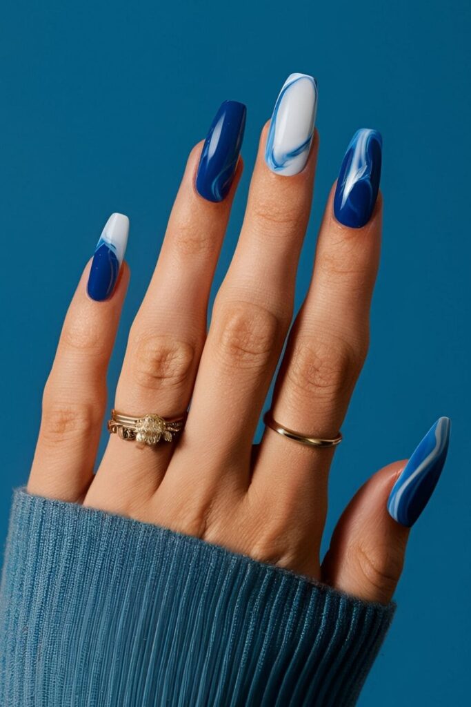 Royal blue nails with swirls of white and blue, creating an elegant marble effect that’s both sophisticated and stylish