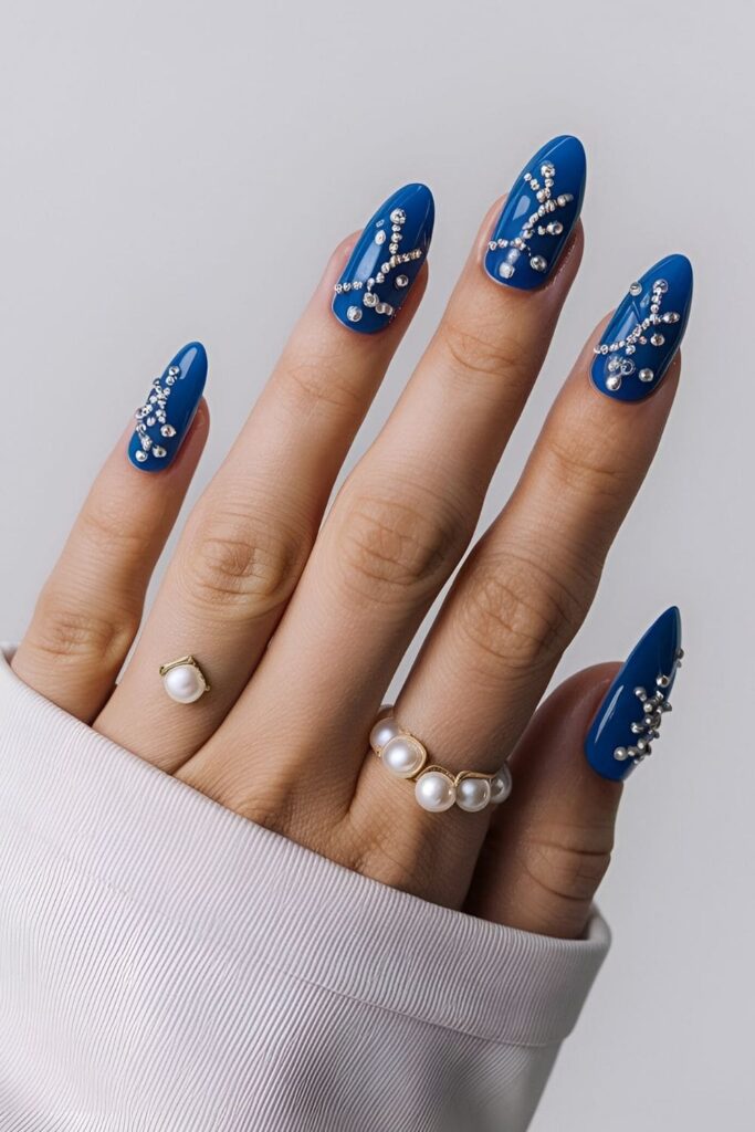 Royal blue nails with tiny pearl embellishments arranged in patterns or at the base of each nail, adding a classy and elegant touch