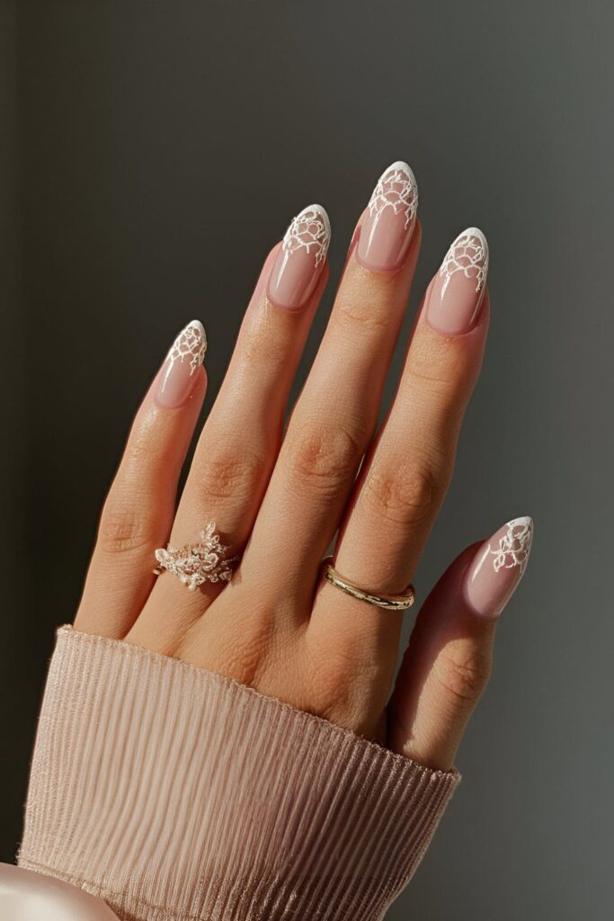 Sheer nude nails with delicate white lace-like designs, creating an elegant and ethereal veil effect