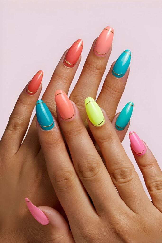 Short acrylic nails in coral, turquoise, and neon pink with gold accents against sun-kissed skin