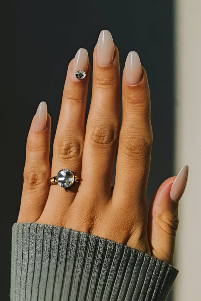 Soft base acrylic nails with a single rhinestone placed near the cuticle, tip, or middle for a minimalist look