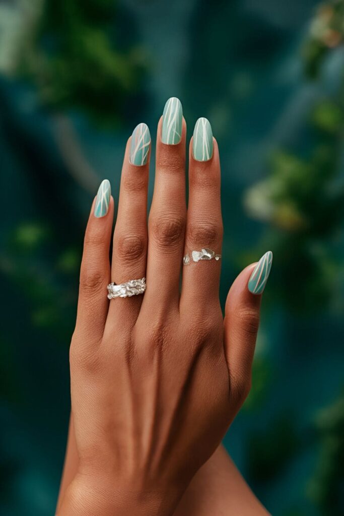 Soft blue and green nails with cascading white lines and fine silver glitter, mimicking an enchanted waterfall

