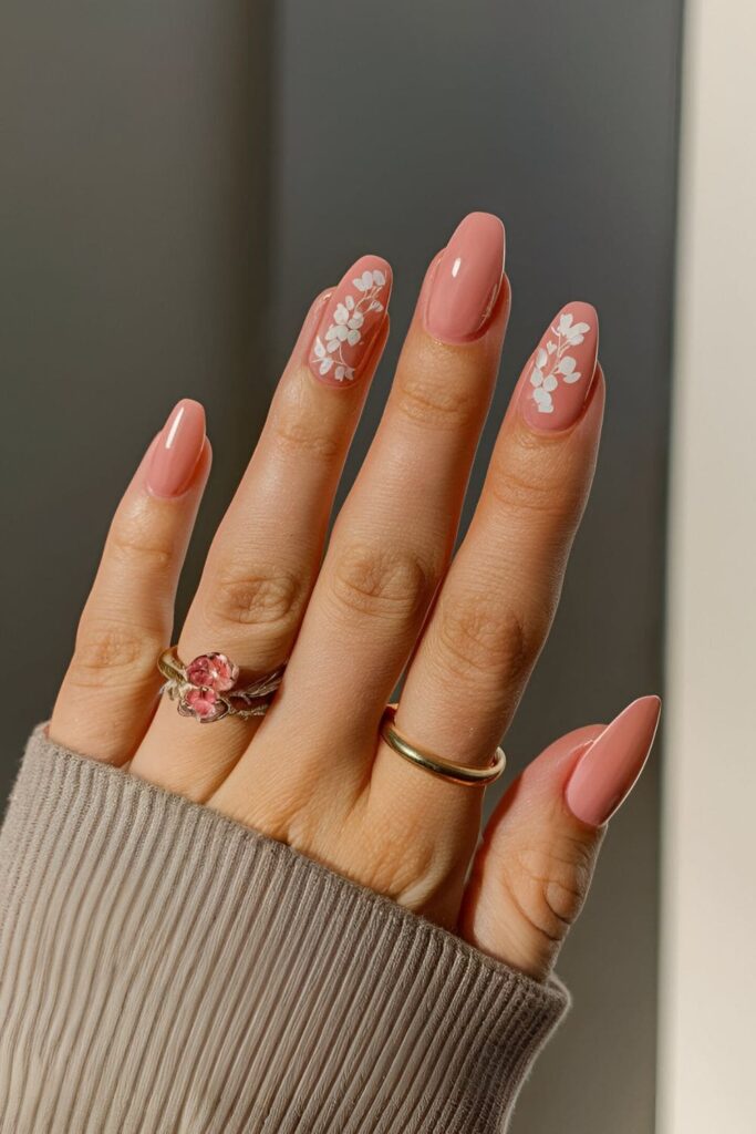 Soft coral base nails with delicate pink and white flowers, creating a warm and inviting look