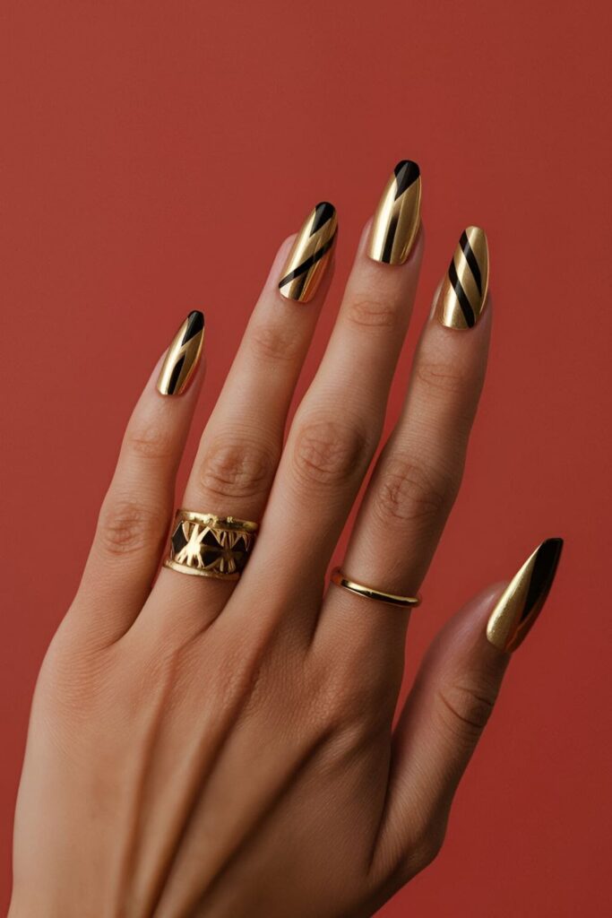 Striking combination of gold and black acrylic nails with geometric designs, ideal for a bold and edgy look