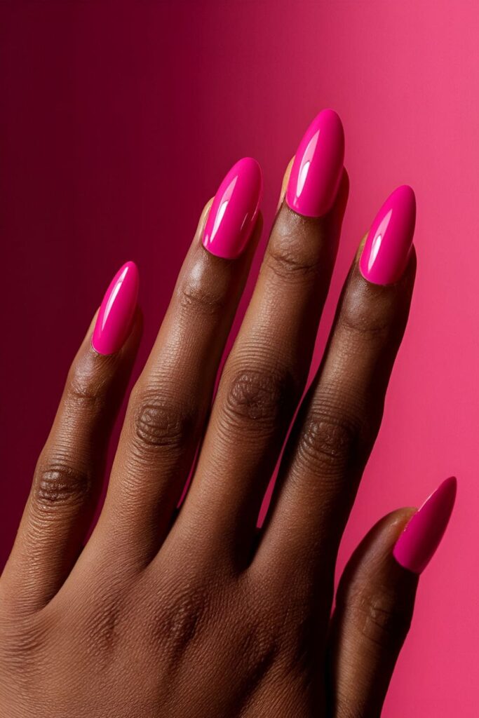 Vibrant hot pink acrylic nails that stand out against dark skin tones, showcasing a bold and attention-grabbing design