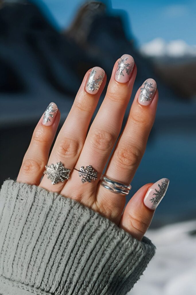 Winter-themed nails with delicate silver snowflake designs on a clear or light-colored base