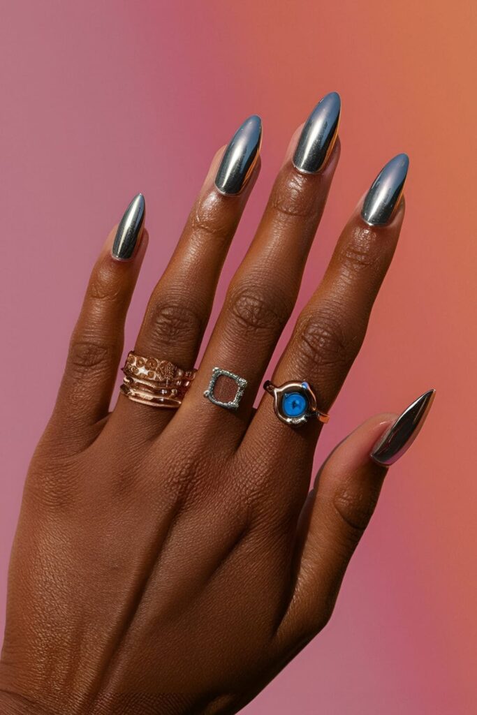 Dark-skinned hands with chrome acrylic nails in silver, rose gold, and vibrant blue shades