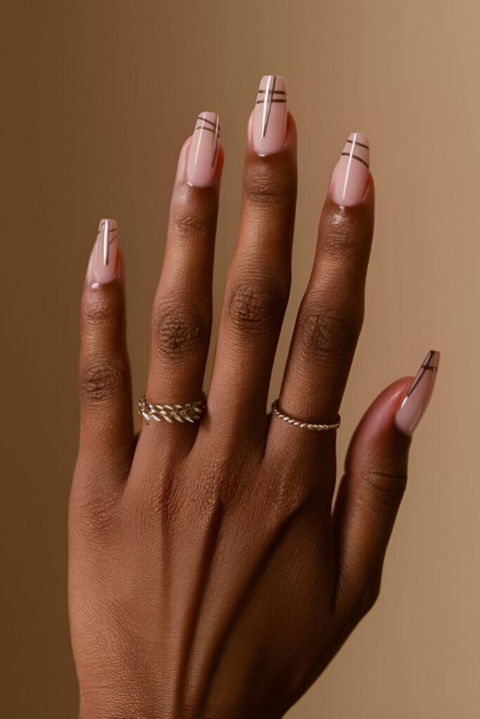 Dark-skinned hands with minimalist line acrylic nails, featuring thin metallic lines in various orientations