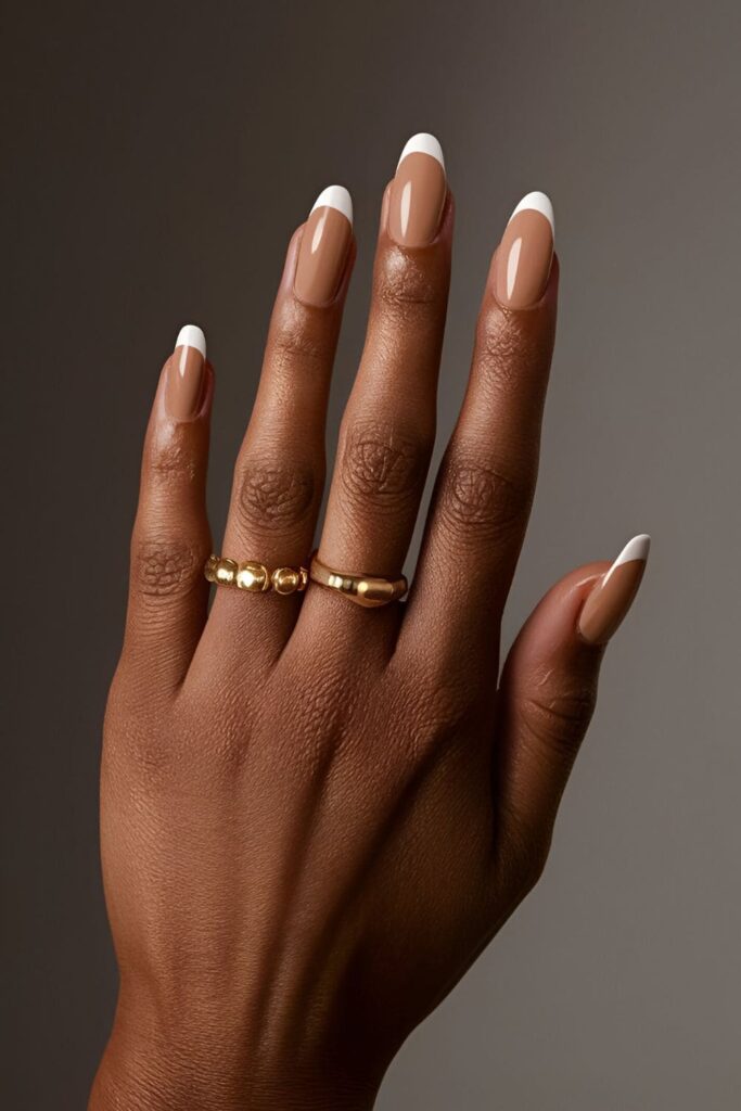 Dark-skinned hands with half-moon manicure acrylic nails, showcasing contrasting colors like nude and white or bold dark shades