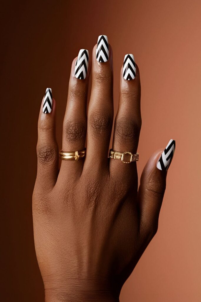 Dark-skinned hands with high-contrast black and white geometric pattern acrylic nails