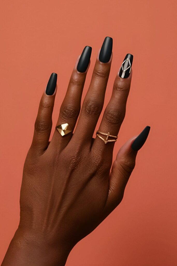 Dark-skinned hands with matte black acrylic nails, paired with geometric and metallic designs