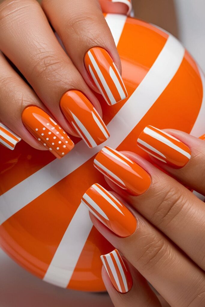 Orange nails with crisp white stripes and dots, stylish and modern acrylic nail design

