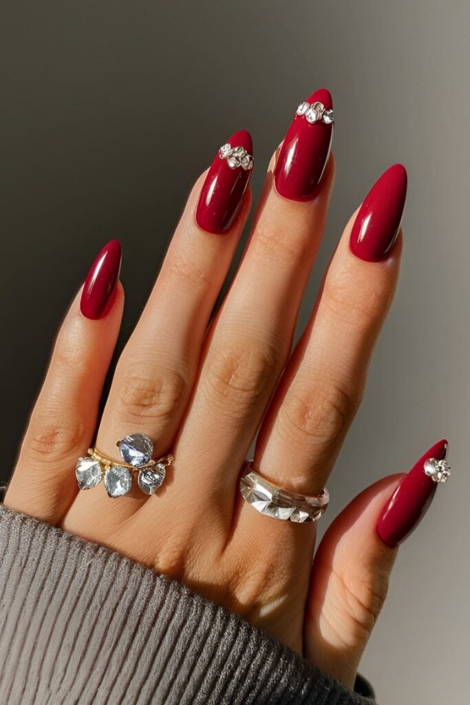 Classic, romantic red acrylic nails with rhinestones for a dazzling touch, featuring single or clustered rhinestones near the cuticle or tips