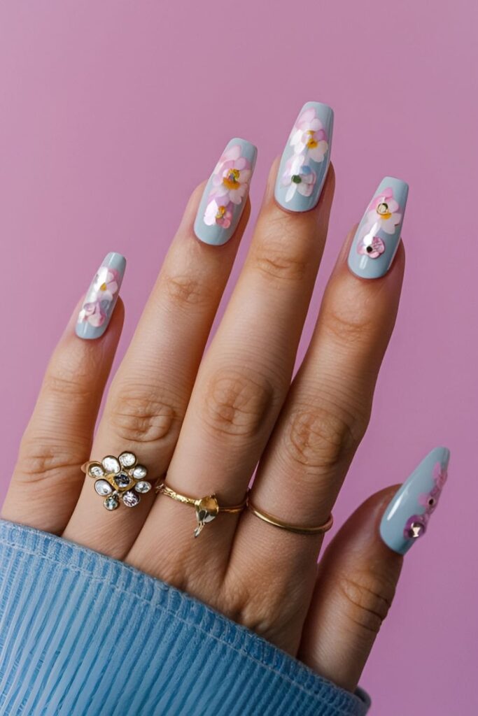 Delicate floral design acrylic nails with pastel colors and rhinestones in the center of each flower, creating a feminine and sparkly effect