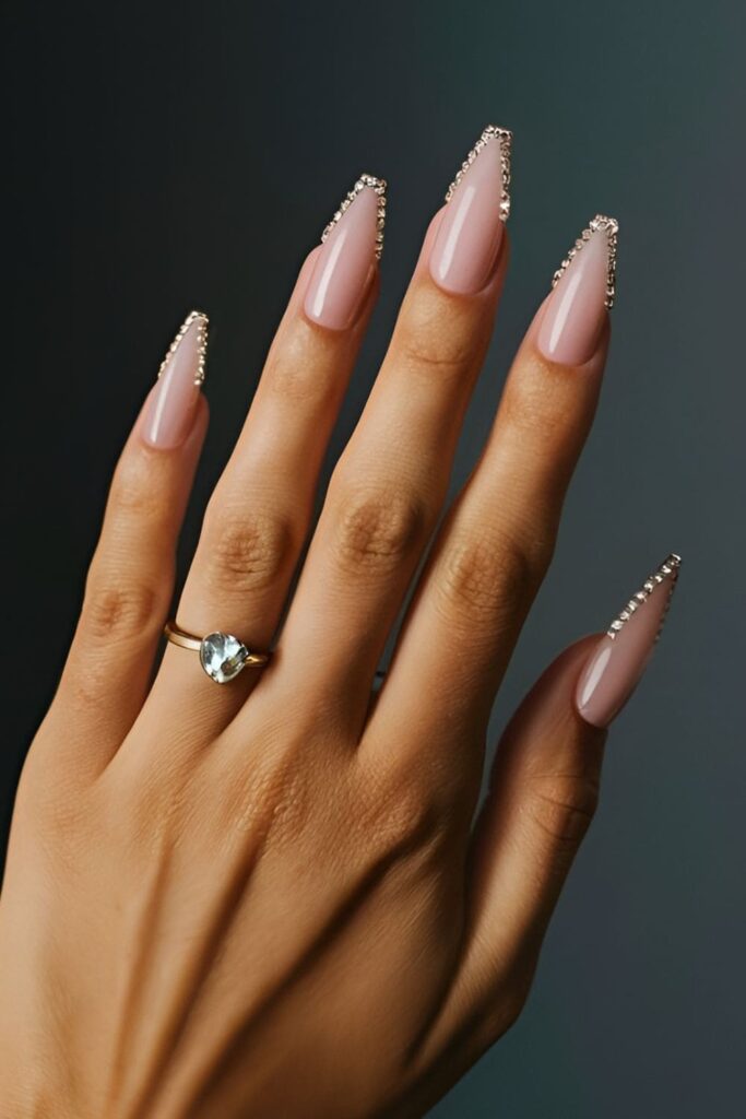 Dramatic stiletto-shaped acrylic nails accented with rhinestones along the edges or tips, naturally drawing attention with their bold, pointed shape