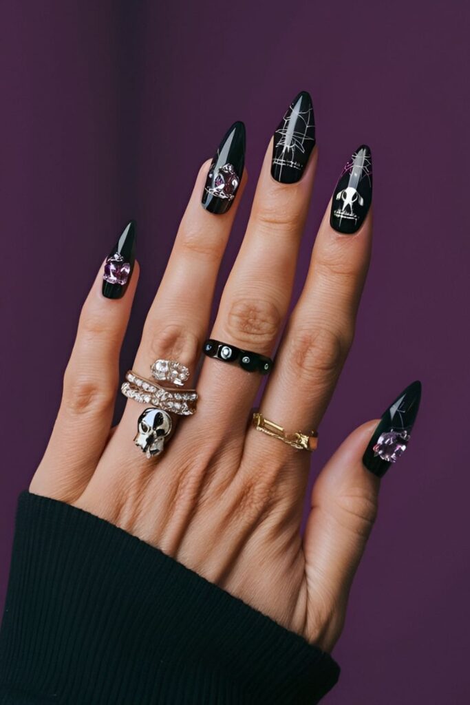 Gothic-inspired acrylic nails with deep blacks and purples, featuring skull or spiderweb patterns and rhinestones for a glam, edgy look