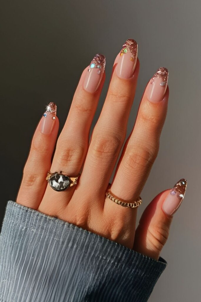 Sparkling gradient acrylic nails with a base color transitioning from glitter at the tips towards the cuticle, finished with rhinestones at the base for a dazzling look
