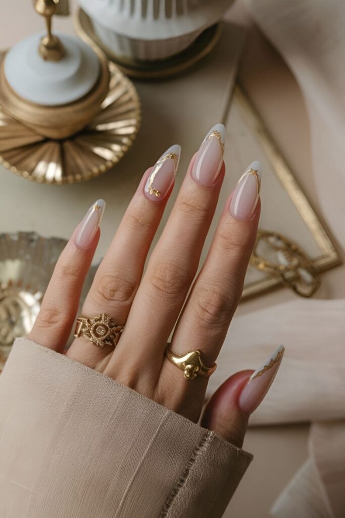 Vintage-inspired acrylic nails with soft ivory bases and delicate gold detailing