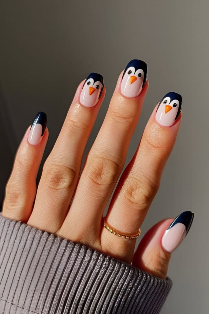 Acrylic nails featuring cute penguin faces on one or two nails, with bright eyes and small beaks