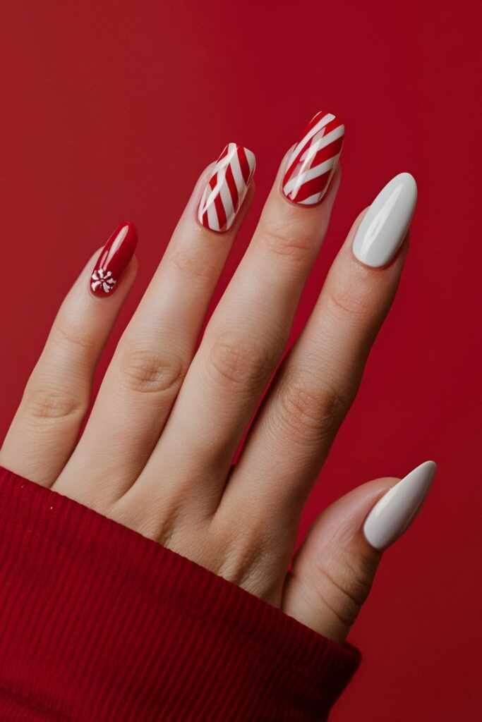 Acrylic nails with red and white candy cane stripes, including one nail with a candy cane accent