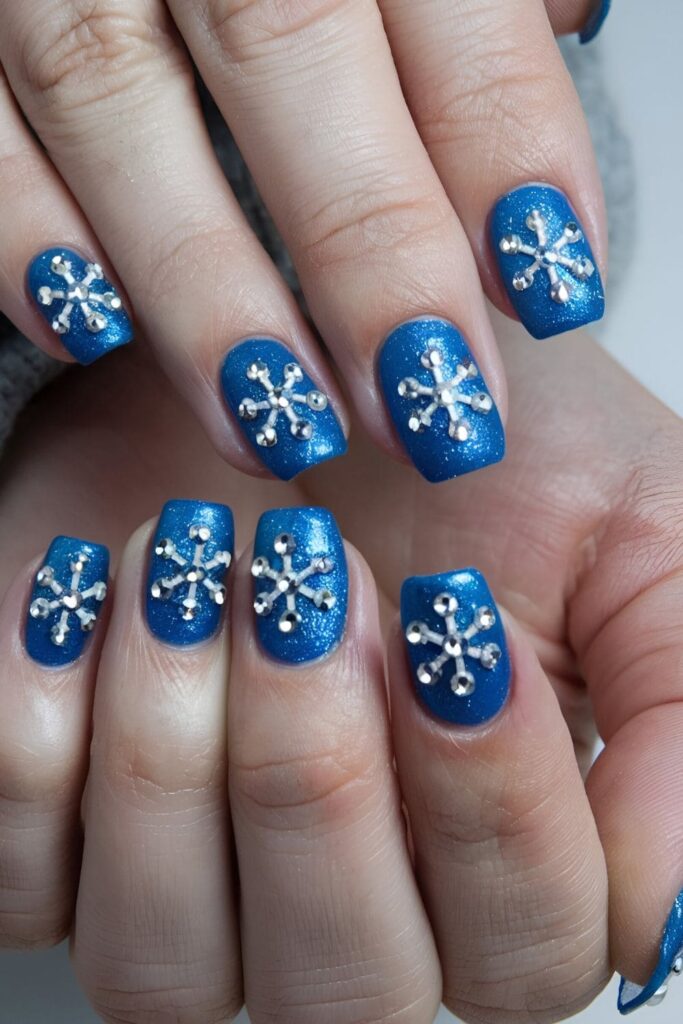 Blue nails adorned with small, strategically placed rhinestones for a subtle, glitzy winter design