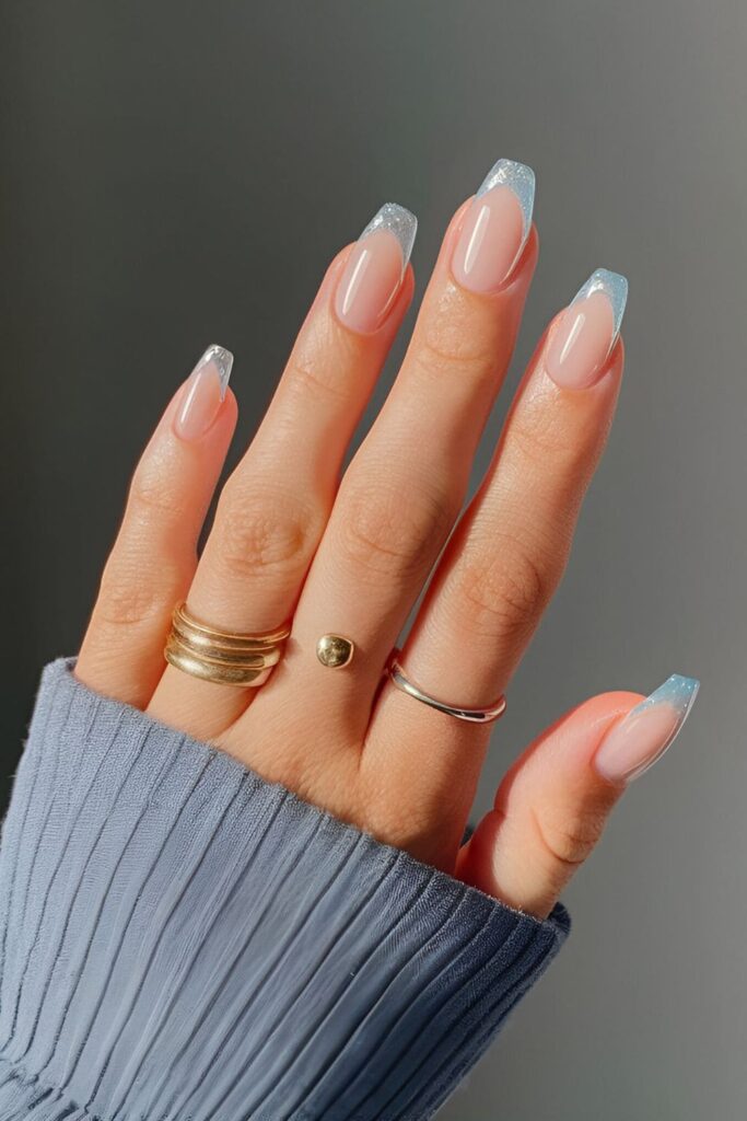 Clear or nude nails with icy blue French tips, a minimalist and seasonal twist on a classic manicure