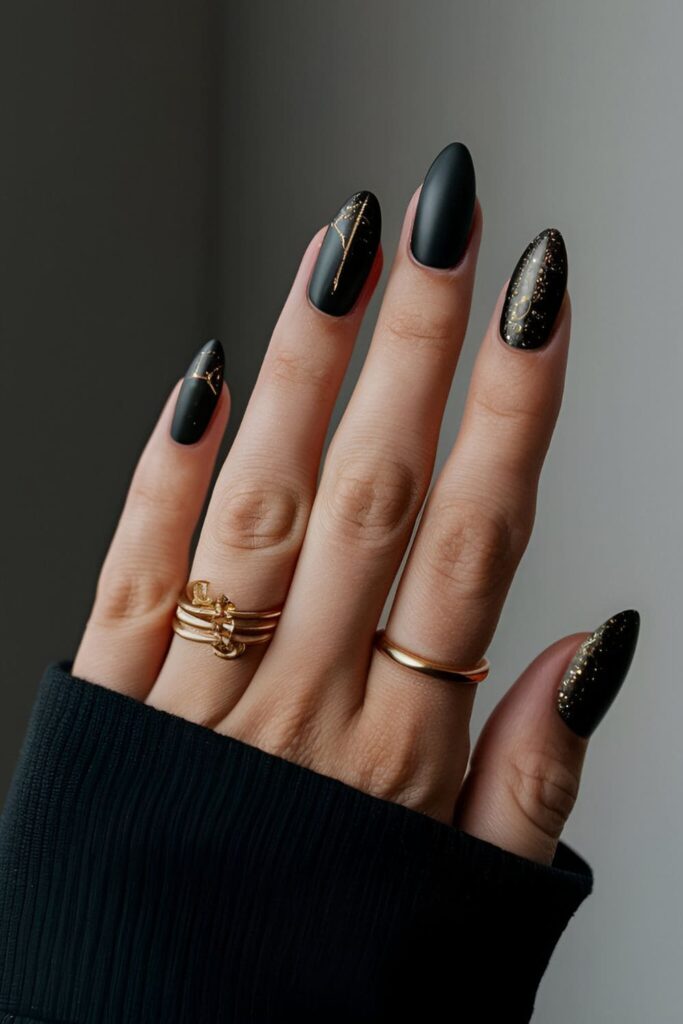 Matte black nails adorned with bold gold accents, creating a dramatic and sophisticated winter design