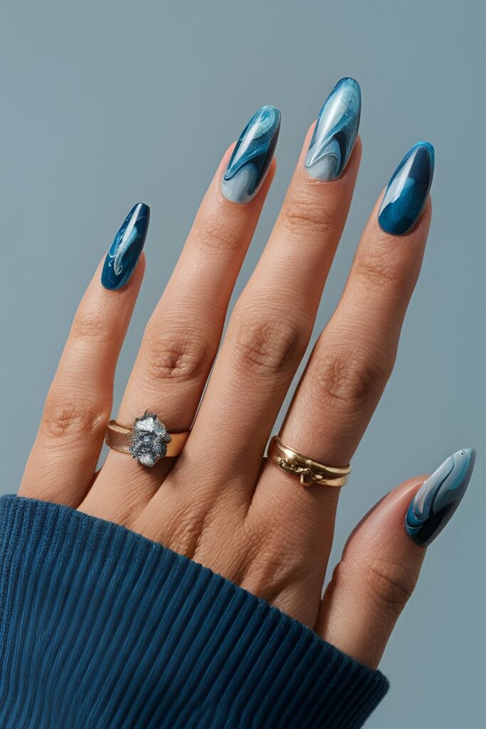 Nails with a blue marble design, swirling together different shades of blue for a sophisticated, icy effect