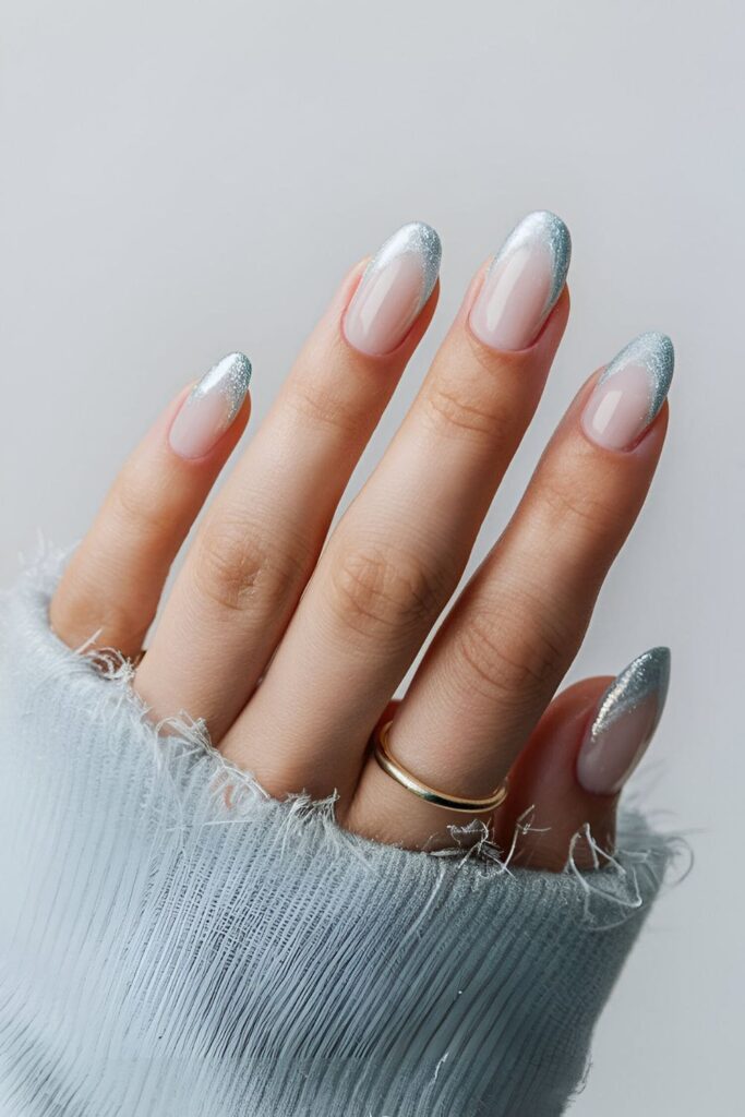 Nails with a pale blue base fading into clear frosted tips, resembling icy winter frost