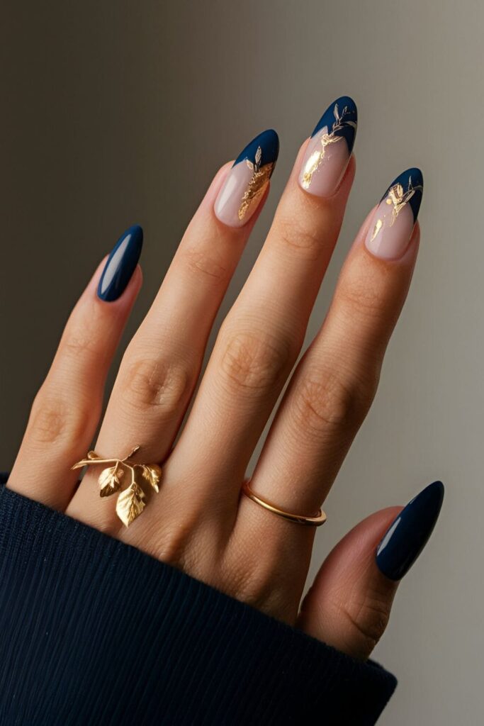 Navy blue nails enhanced with delicate gold leaf accents, placed at the tips or base for an elegant look