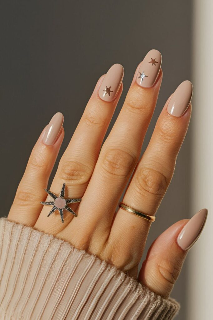 Nude nails decorated with tiny metallic star symbols in gold and silver, creating a celestial and enchanting design