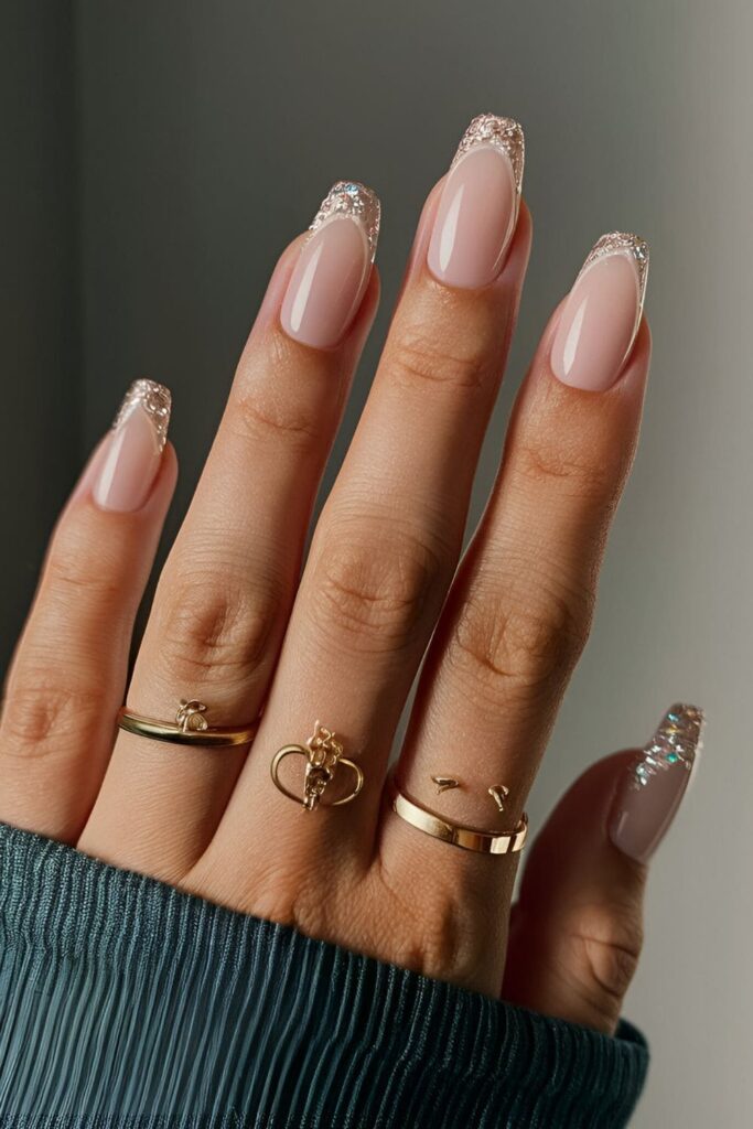 Nude nails with French tips and a thin glitter line just below the tip, adding a modern and glamorous twist to the classic look