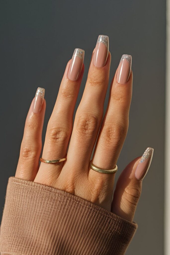 Nude nails with a soft glitter ombre effect, gradually fading from glittery tips to the nude base for a subtle, sparkling look