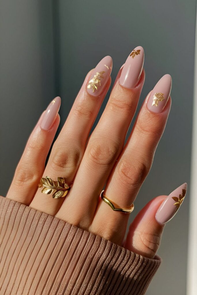 Nude nails with luxurious gold leaf accents applied to a few accent nails, creating an artistic and high-end look