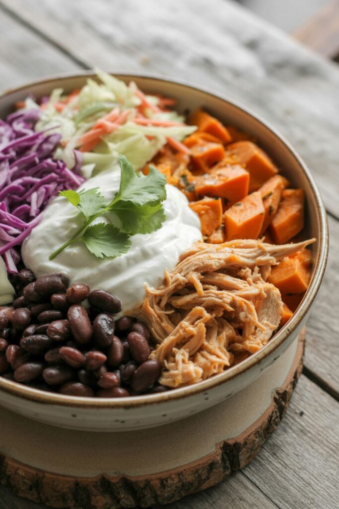 BBQ shredded chicken bowl with roasted sweet potatoes, black beans, coleslaw, and Greek yogurt
