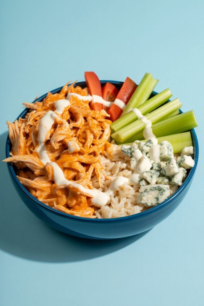 Buffalo chicken bowl with rice, blue cheese, celery, and a drizzle of ranch dressing
